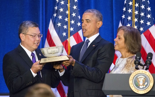 President Barack Obama center is presented a commemorative bowl from Rep. Mark Takai D Hawaii left and Rep. Robin Lynne Kelly D-N.Y. right before